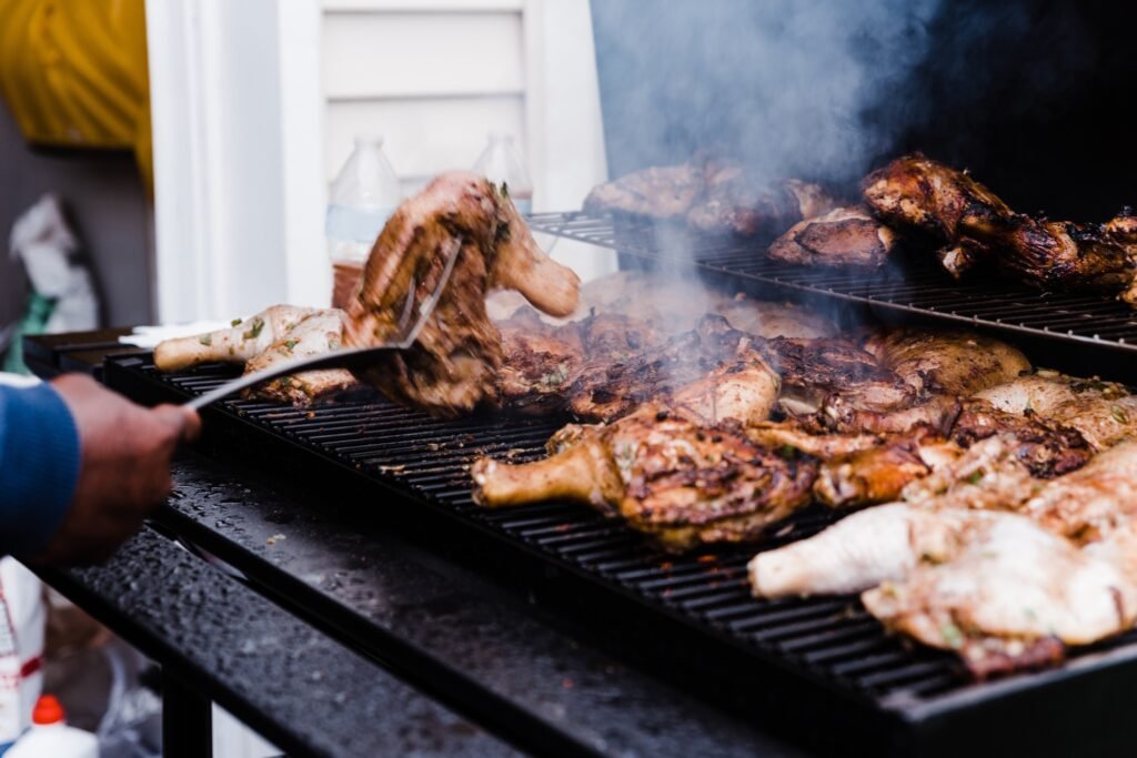 Black man on a nice summer day jerking chicken on open grill